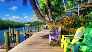 A wooden pier extending into a body of water, with colorful chairs and umbrellas along the side. - Luxury, Private Suite in cool Palm Beach Gardens with WiFi, AC (Palm Beach Gardens)