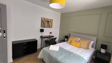 Un dormitorio moderno con cama, mesitas de noche, escritorio y silla.
