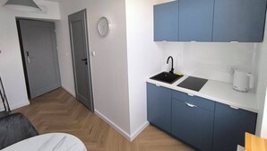 Une cuisine moderne avec des meubles bleus, un évier noir et un plan de travail blanc.
