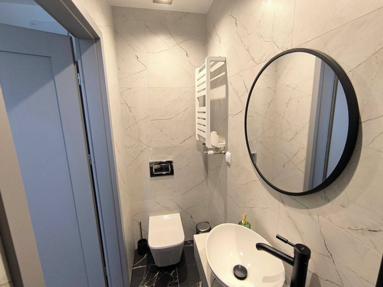 A bathroom with a toilet, sink, and mirror.