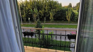 Un balcon donnant sur une route et sur un espace verdoyant.