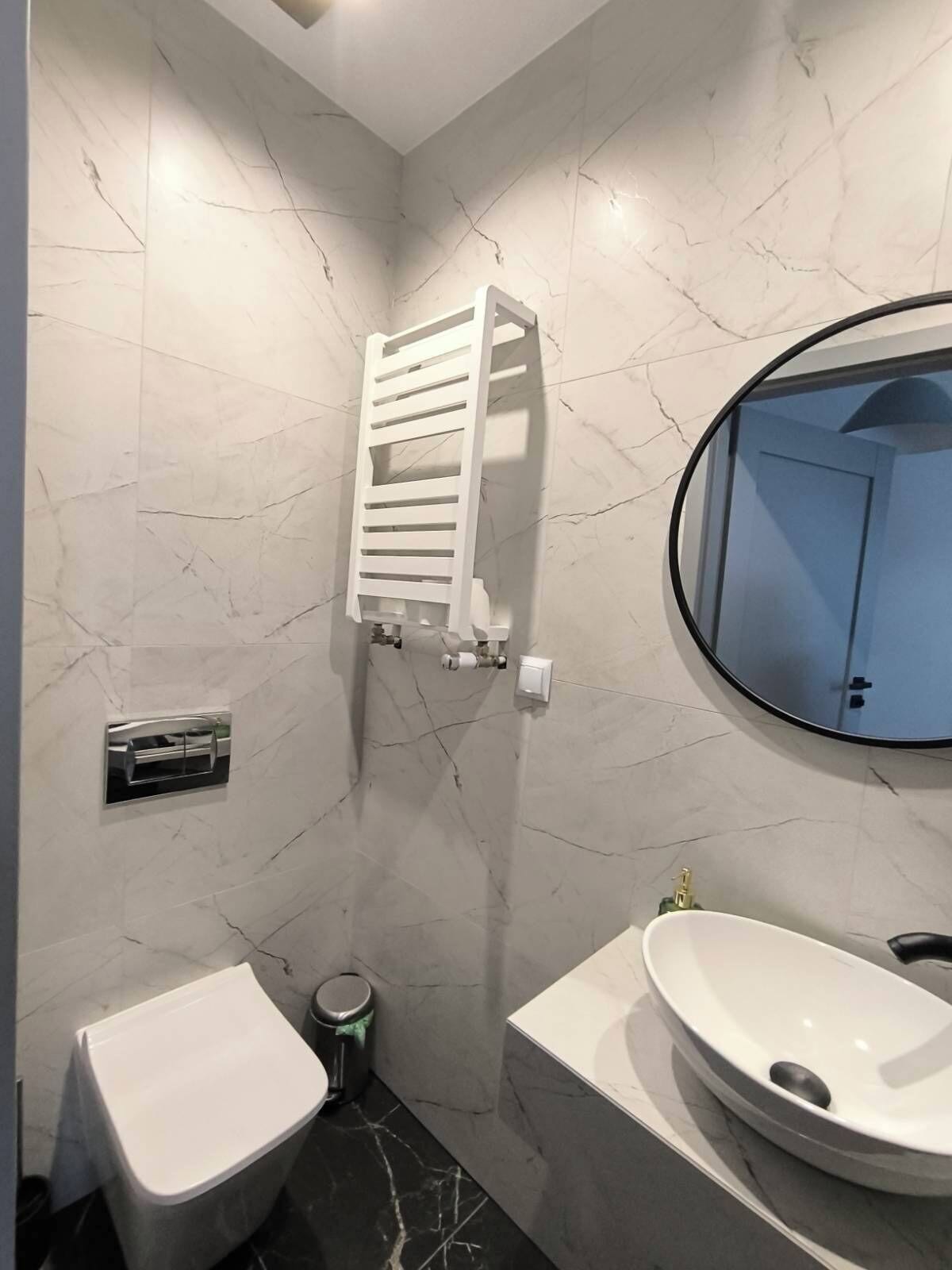 Et badeværelse med toilet, bidet og håndvask, alt med moderne armaturer.
