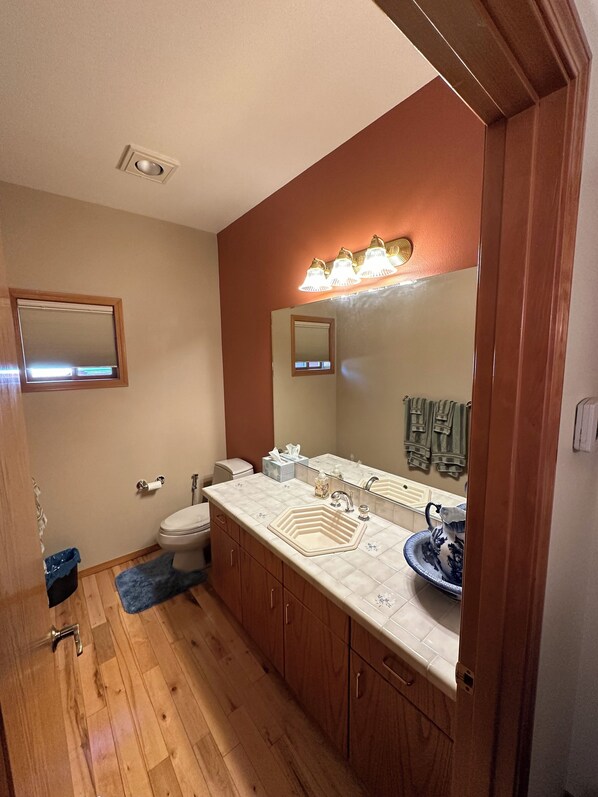 A bathroom with a wooden vanity, a large mirror, and a sink.