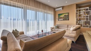 Ein geräumiges Wohnzimmer mit großem Fenster, einer Couch, einem Couchtisch und einem Bücherregal.