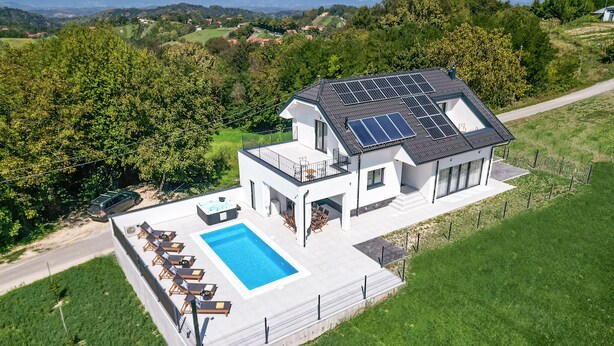 Ein modernes, zweistöckiges Haus mit Swimmingpool, Solaranlage und schöner Aussicht auf die Landschaft.