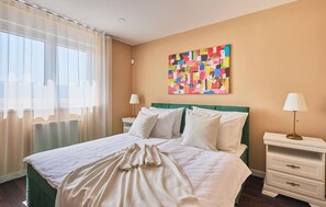 A hotel room with a bed, a nightstand, a lamp, a colorful abstract painting, and sheer curtains. - Beautiful home in Gornja Stubica with sauna (Gornja Stubica)