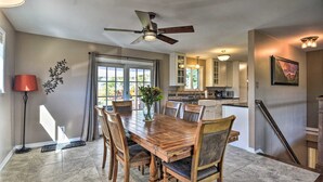 A dining area with a wooden table and chairs, a ceiling fan, and a view of the kitchen and outdoor space. - Spacious Oasis, 5-bedroom house in Boulder with Views, 5.5 miles from Pearl St (Boulder)
