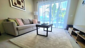 A living room with a sofa, a coffee table, a lamp, and a view of the outdoors through large windows. - Fantastic view of the pool vr222 h+c
 (Bayahibe)