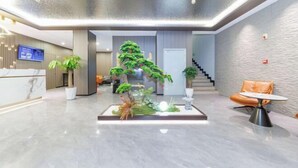 Un vestíbulo moderno con mostrador de recepción, una escalera y una zona de estar con una pequeña mesa.