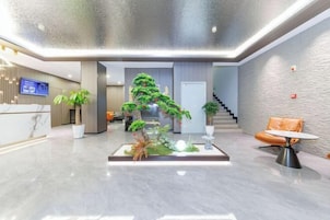 Un vestíbulo moderno con mostrador de recepción, una escalera y una zona de estar con una pequeña mesa.