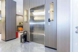 Un elevador moderno con acabados metálicos e iluminación empotrada en la pared.