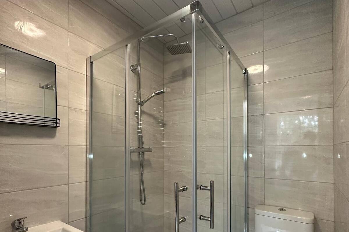 A modern bathroom with a glass-enclosed shower, a white sink, and a toilet.