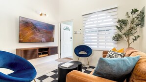 A living room with a large TV, a blue chair, a brown sofa, and a small table. - Sunset at ArecaHomes~ Beach Access~ Pool & Water Park (Discovery Bay)