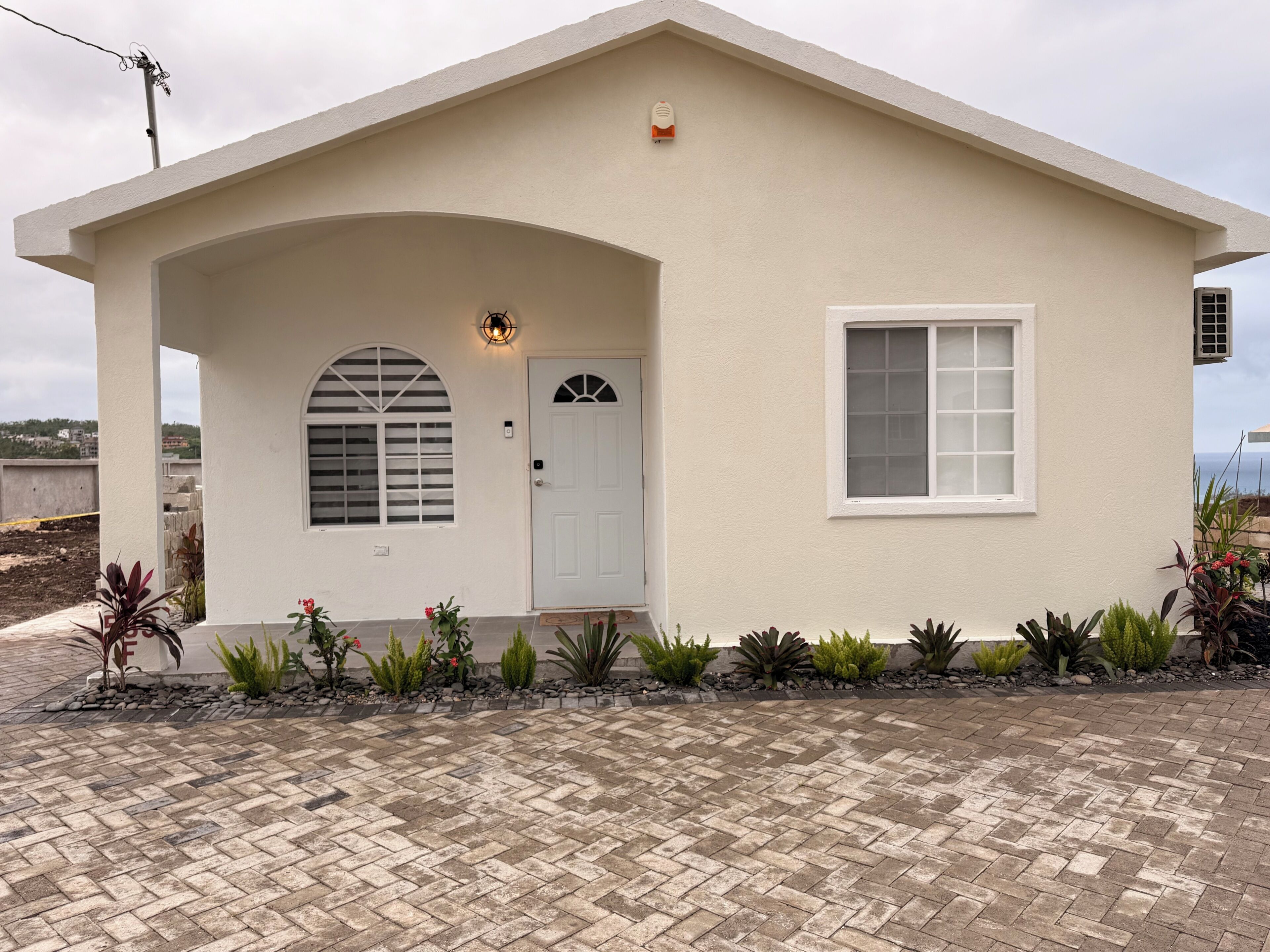 A single-story house with a white facade, a front door, a window, and a small porch area.
