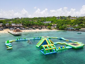 Une plage dotée d’aires de jeux aquatiques, d’un rivage sablonneux et d’un décor composé d’immeubles et d’arbres.