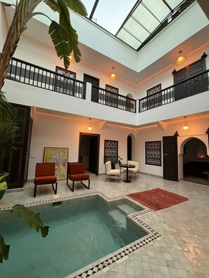 A spacious indoor area with a pool, seating, and a balcony. - Riad Awatif le 36 (Marrakech)