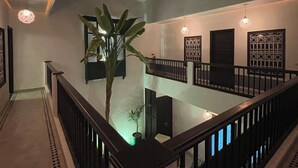 Un interior espacioso con techo alto, una escalera central y vista a un nivel inferior.