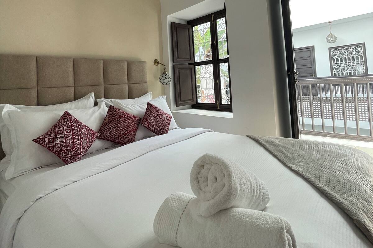 A hotel room with a large bed, a window with a view, and a balcony.