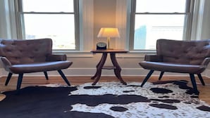 Una habitación con dos sillones de cuero, una mesa de madera con una lámpara y un tapete de cuero de vaca.