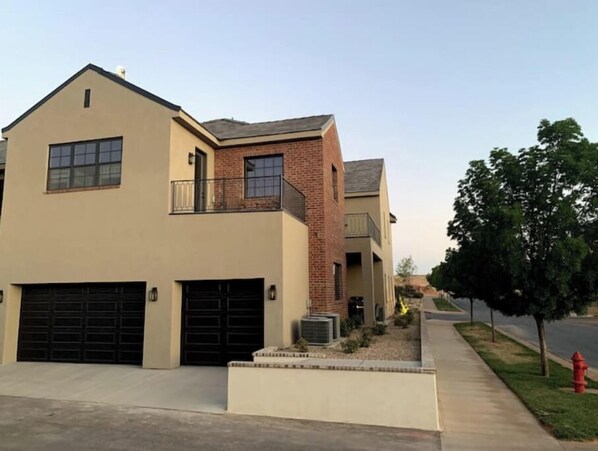 A two-story residential building with a beige facade, a brick section, and a visible garage.