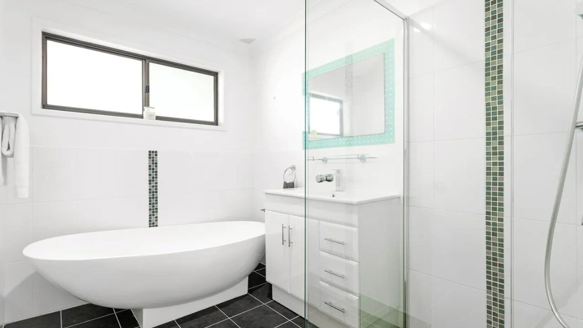 Un bagno moderno con una vasca freestanding, un box doccia in vetro e un lavabo con specchio.