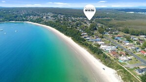 Vista aérea de un pueblo costero con playa, casas y cielo despejado.