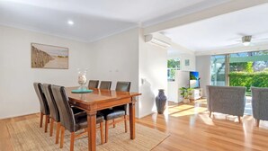 Un comedor amplio con una mesa y sillas de madera, un jarrón grande y un cuadro en la pared.