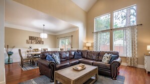 A spacious living room with a leather sectional sofa, a wooden coffee table, and a dining area in the background. - Serenity Awaits: Pine Trees Retreat w/ AC and EV (Flagstaff)