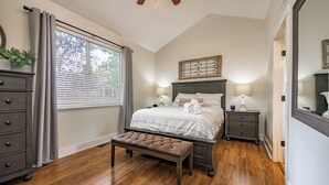 A bedroom with a bed, bedside tables, a bench, a dresser, and a window with blinds. - Serenity Awaits: Pine Trees Retreat w/ AC and EV (Flagstaff)