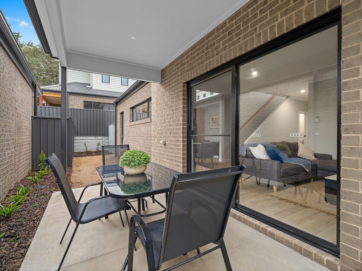 Une terrasse moderne avec une table en verre, des chaises et une plante en pot.