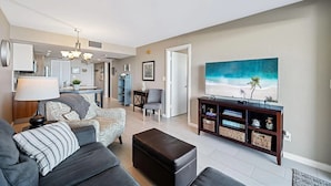 A modern living room with a sofa, ottoman, and a TV stand with decorative items. - Beachfront paradise in this gorgeous renovated ground floor condo! (Marco Island)