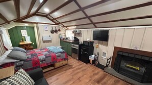 Habitació senzilla amb llit, sofà, cuineta i llar de foc.