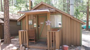 Una petita cabana de fusta amb un porxo, una porta i una finestra.