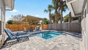 A backyard with a swimming pool, patio furniture, and a pergola. - Beach Getaway w Pool | Good Morning Rentals (Jacksonville Beach)