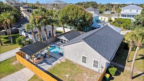 A residential property with a covered patio, a swimming pool, and a large tree in the backyard. - Beach Getaway w Pool | Good Morning Rentals (Jacksonville Beach)
