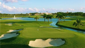A golf course with sand bunkers, a water hazard, and palm trees. - Luxury, Private Suite 2 (Palm Beach Gardens)