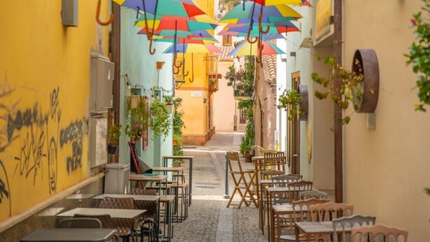 A narrow alley with tables and chairs, colorful umbrellas hanging overhead, and potted plants along the walls. - PV9: One-Bedroom Apartment with Romantic Terrace in the City Center (Olbia)