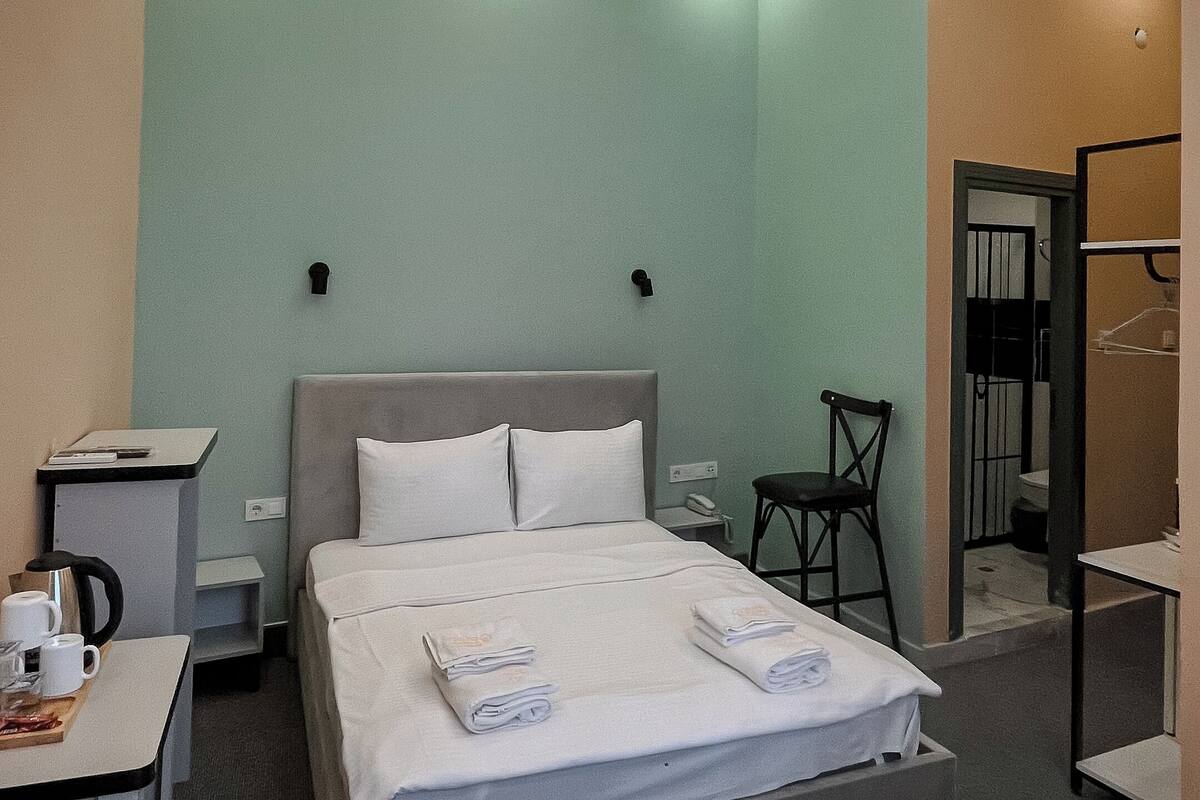 A hotel room with a large bed, bedside tables, a desk, and a chair.