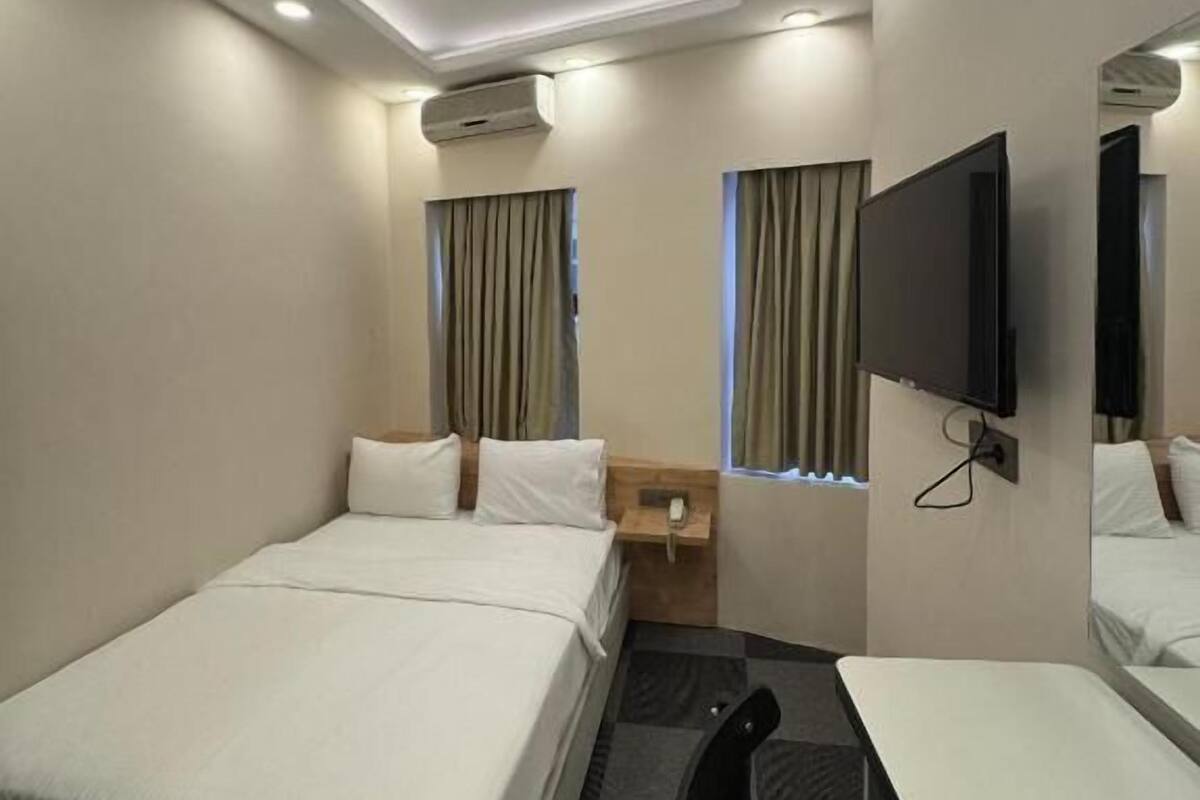 A hotel room with two beds, a desk, a chair, a TV, and a small table with a phone.