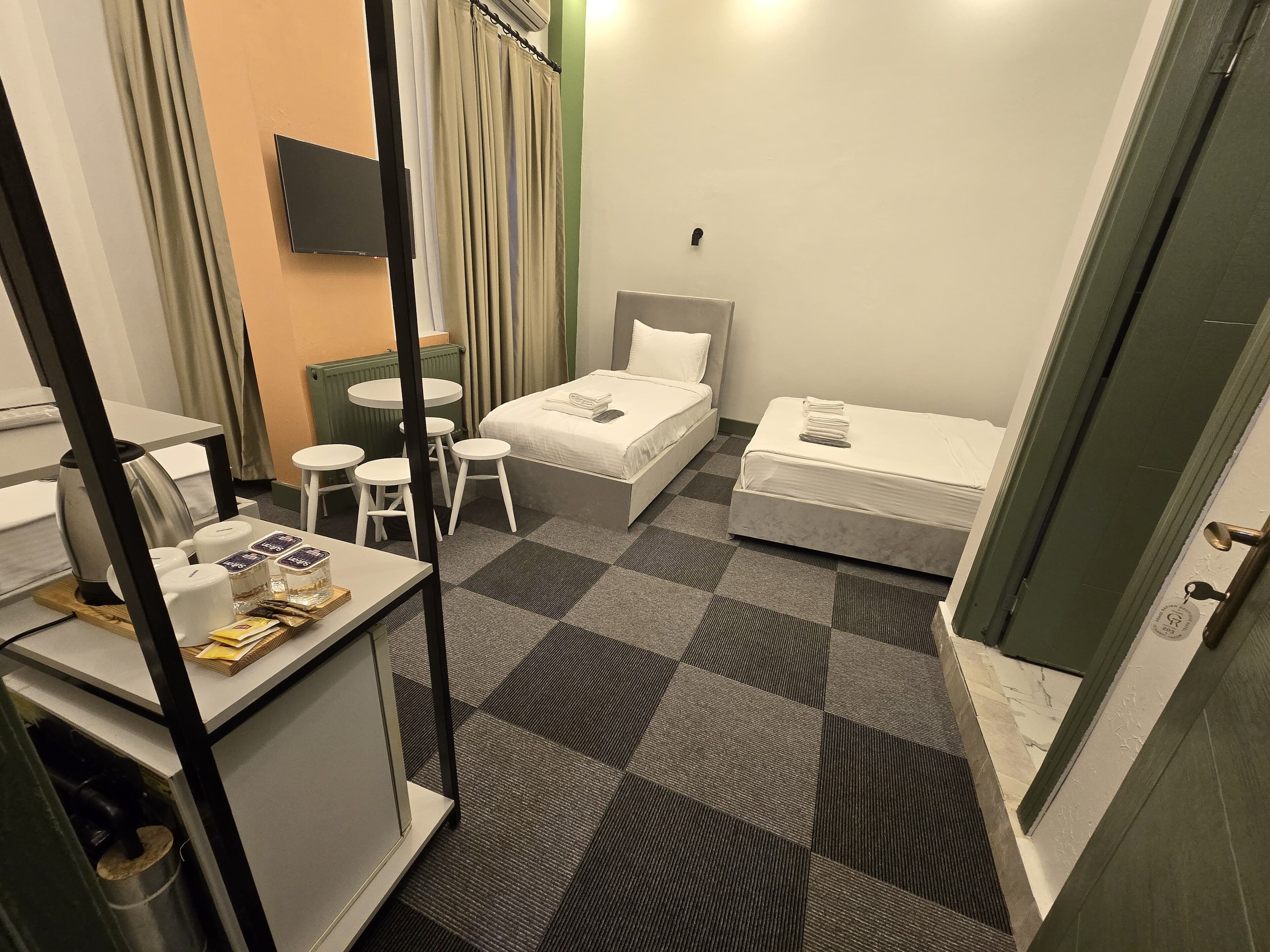 Une chambre d’hôtel avec deux lits, un bureau, une chaise, une petite table et un téléviseur.
