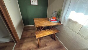 Ein kleiner Essbereich aus Holz mit einer Bank und einem Tisch, ein gerahmtes Bild an der Wand und ein Schild mit der Aufschrift 'CABIN 4'.