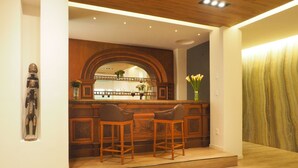 Een moderne keuken met een houten bar, twee barkrukken en een decoratieve spiegel boven het aanrecht.