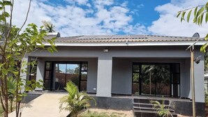 A modern two-story house with a flat roof, large windows, and a concrete driveway.