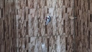 A bathroom with a marble wall, a showerhead, and a toilet.