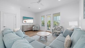 Uma sala de estar moderna com um sofá azul claro, uma mesa de centro redonda e poltronas estampadas.