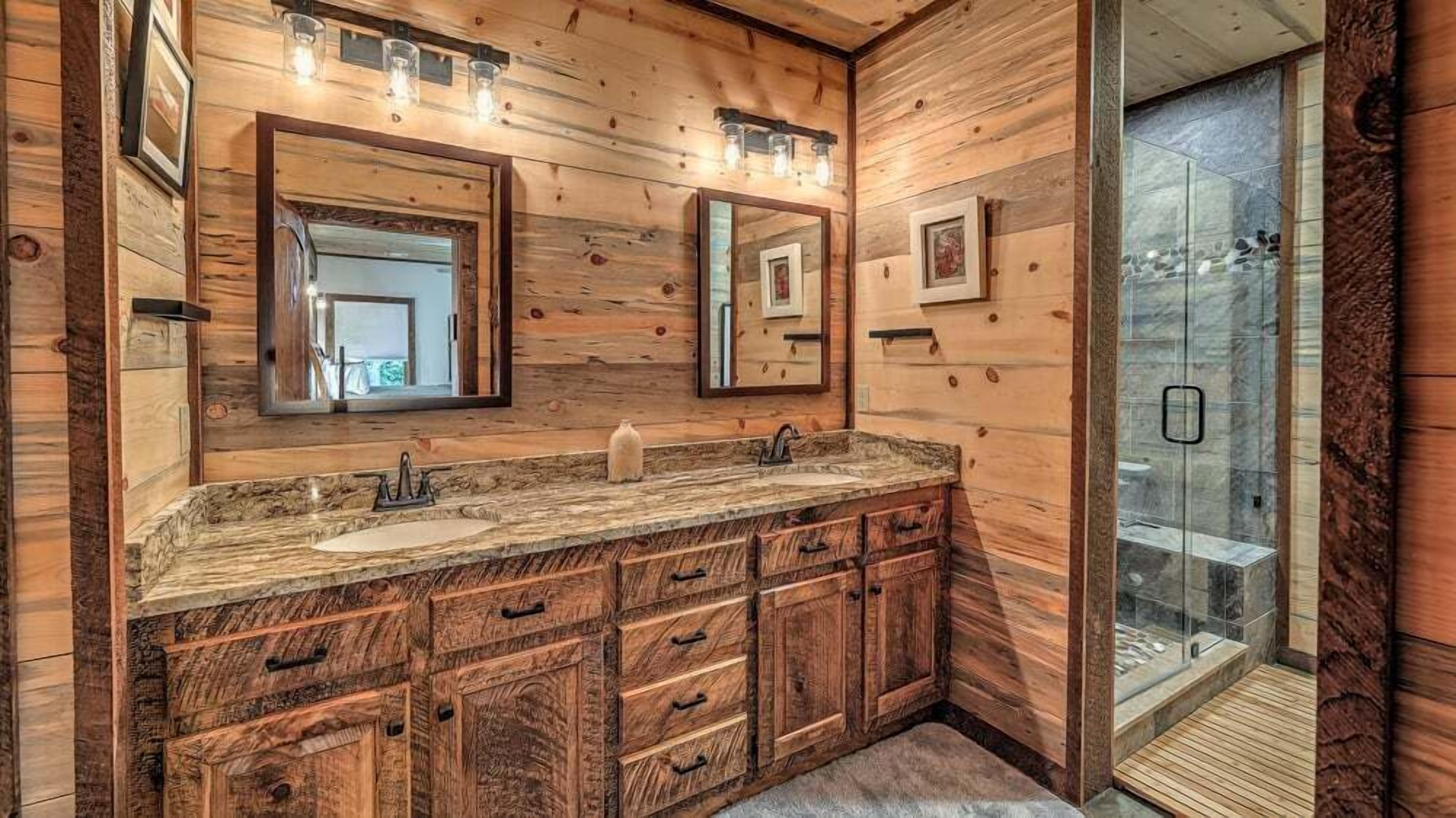 Une salle de bain en bois avec deux lavabos, un grand miroir et une douche à parois de verre.