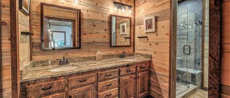 Une salle de bain en bois avec deux lavabos, un grand miroir et une douche à parois de verre.
