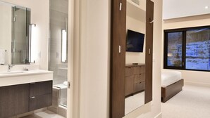 Une chambre moderne avec un grand miroir, une télévision et une fenêtre donnant sur un paysage enneigé.
