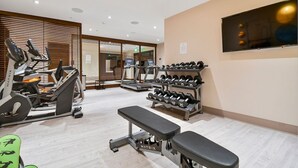 Une salle de sport équipée de tapis de course, d’haltères et de bancs.