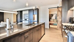 A modern kitchen with a large island, stainless steel appliances, and pendant lighting.